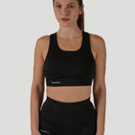 Woman wearing a black sustainable sports bra and biker shorts set